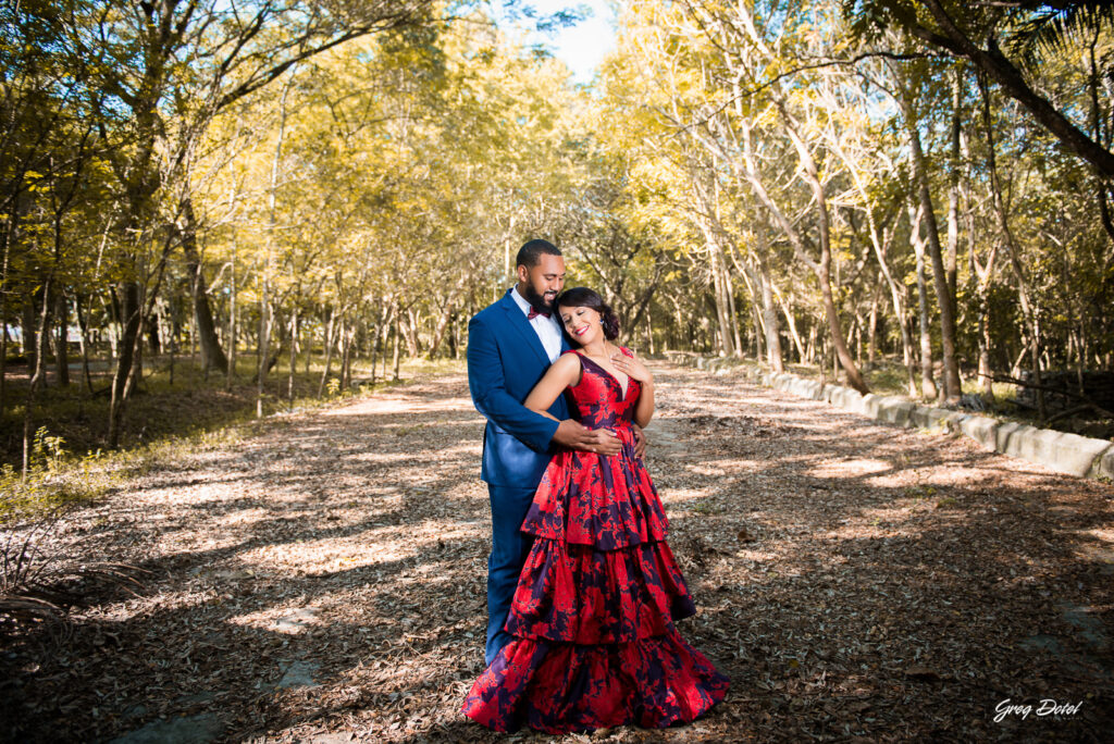 Sesión de fotos pre boda o novios en el Parque Humedales del Ozama en Santo Domingo, República Dominicana por el fotografo dominicano Greg Dotel Photography. Fotos de novios en el parque con traje de novia rojo con flores y traje de caballero.