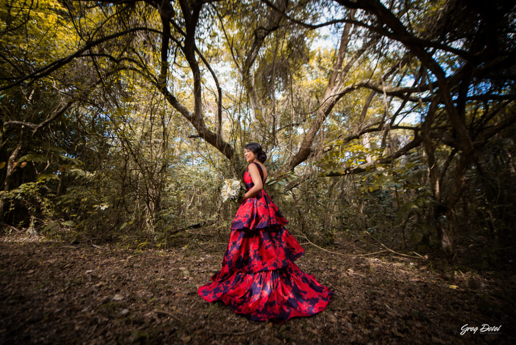Sesión de fotos pre boda o novios en el Parque Humedales del Ozama en Santo Domingo, República Dominicana por el fotografo dominicano Greg Dotel Photography. Fotos de novios en el parque con traje de novia rojo con flores y traje de caballero.