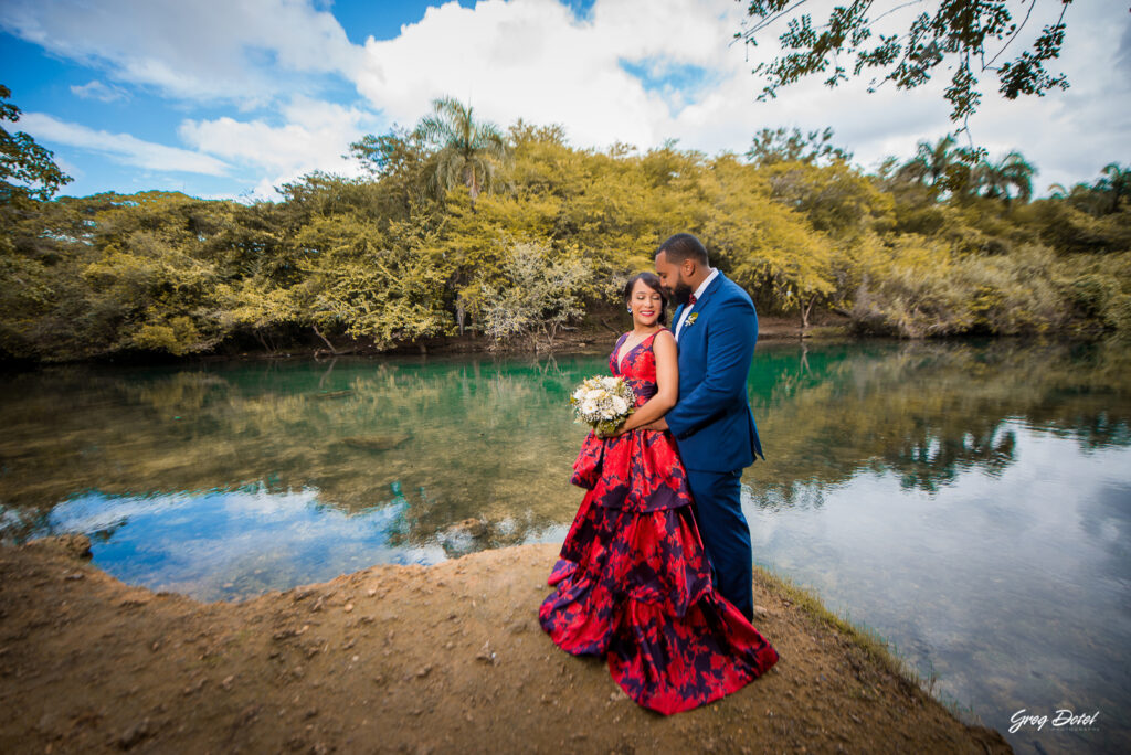 Sesión de fotos pre boda o novios en el Parque Humedales del Ozama en Santo Domingo, República Dominicana por el fotografo dominicano Greg Dotel Photography. Fotos de novios en el parque con traje de novia rojo con flores y traje de caballero.