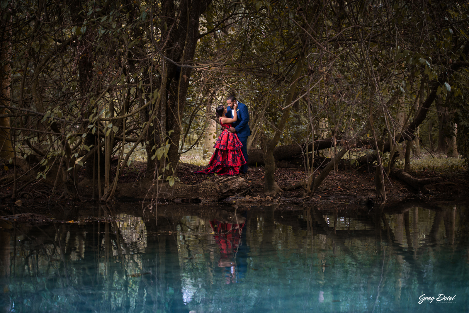 Sesión de fotos pre boda o novios en el Parque Humedales del Ozama en Santo Domingo, República Dominicana por el fotografo dominicano Greg Dotel Photography. Fotos de novios en el parque con traje de novia rojo con flores y traje de caballero.