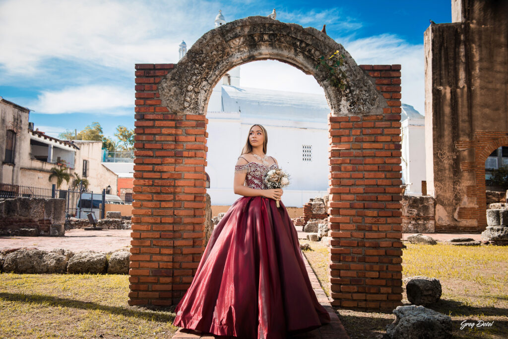 Quinceañera en las Ruinas del Hospital San Nicolas de Bari en la Zona Colonial de Santo Domingo, República Dominicana en su sesión de fotos profesional con elegante vestido rojo de 15 años