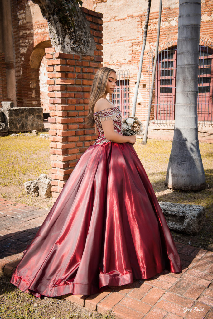 Quinceañera en las Ruinas del Hospital San Nicolas de Bari en la Zona Colonial de Santo Domingo, República Dominicana en su sesión de fotos profesional con elegante vestido rojo de 15 años