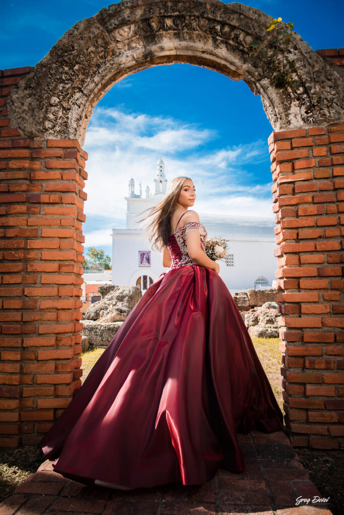 Quinceañera en las Ruinas del Hospital San Nicolas de Bari en la Zona Colonial de Santo Domingo, República Dominicana en su sesión de fotos profesional con elegante vestido rojo de 15 años
