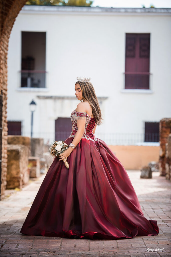 Quinceañera en las Ruinas del Hospital San Nicolas de Bari en la Zona Colonial de Santo Domingo, República Dominicana en su sesión de fotos profesional con elegante vestido rojo de 15 años