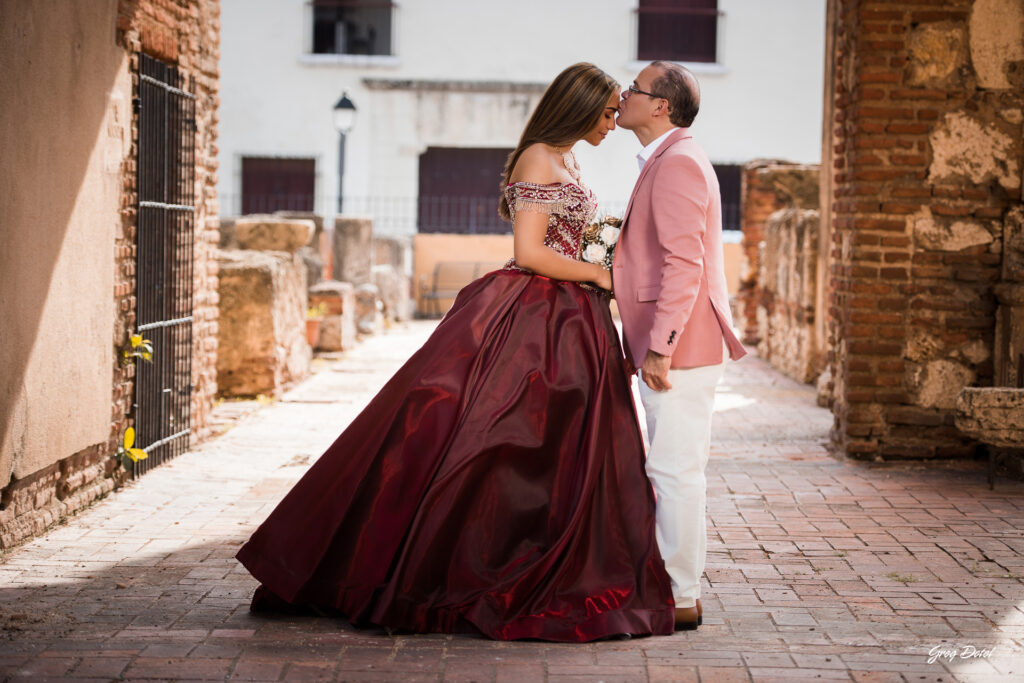Fotos de padre e hija de Quinceañera en las Ruinas del Hospital San Nicolas de Bari en la Zona Colonial de Santo Domingo, República Dominicana en su sesión de fotos profesional con elegante vestido rojo de 15 años