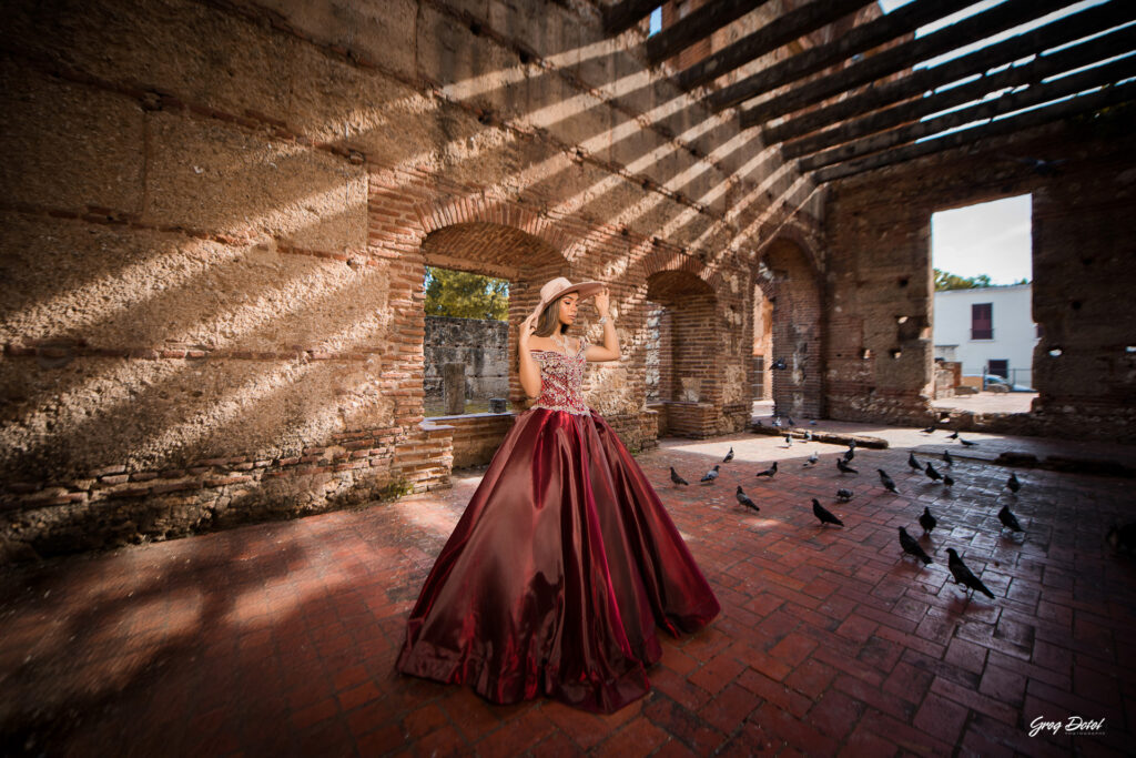 Quinceañera en las Ruinas del Hospital San Nicolas de Bari en la Zona Colonial de Santo Domingo, República Dominicana en su sesión de fotos profesional con elegante vestido rojo de 15 años