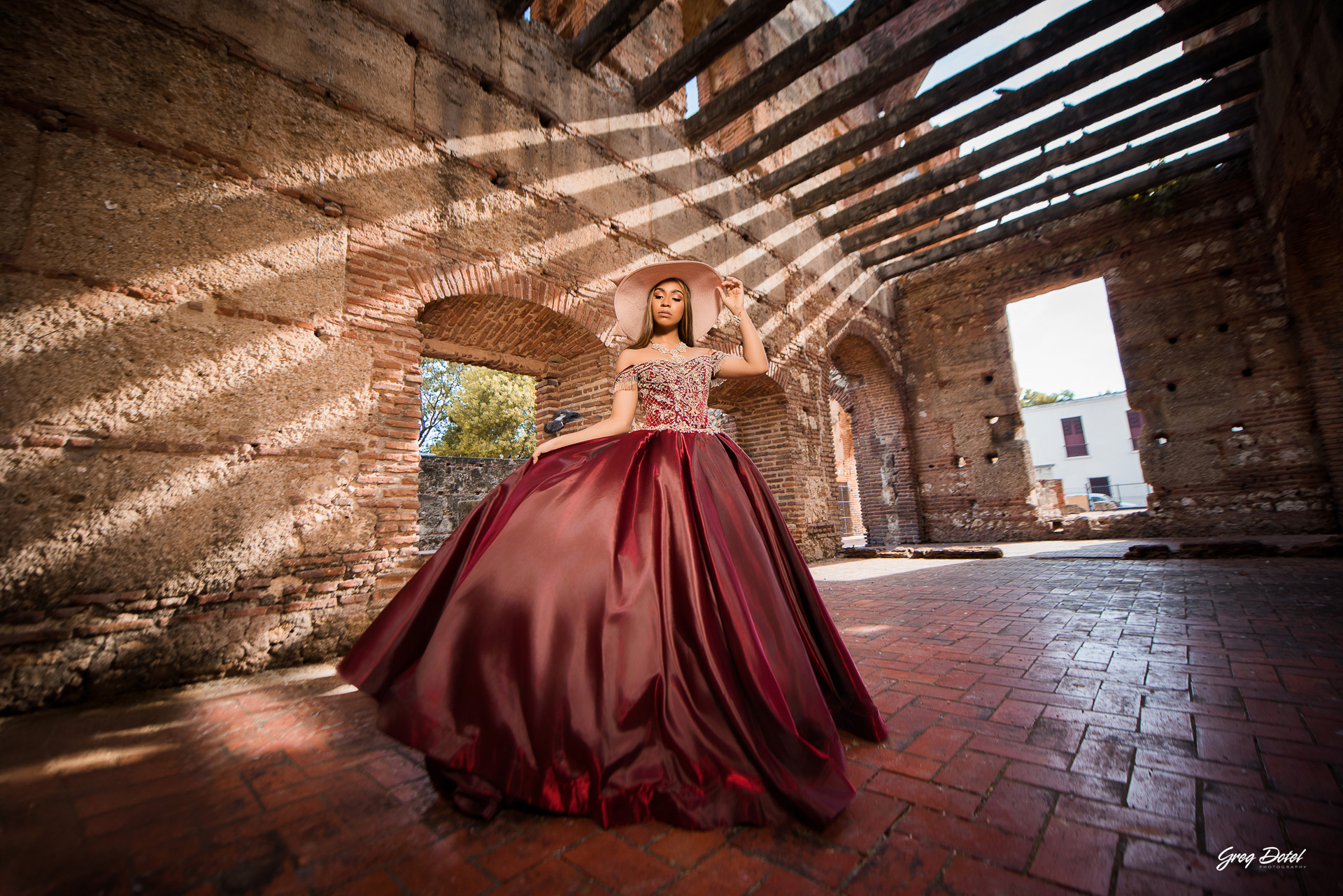 Quinceañera en las Ruinas del Hospital San Nicolas de Bari en la Zona Colonial de Santo Domingo, República Dominicana en su sesión de fotos profesional con elegante vestido rojo de 15 años