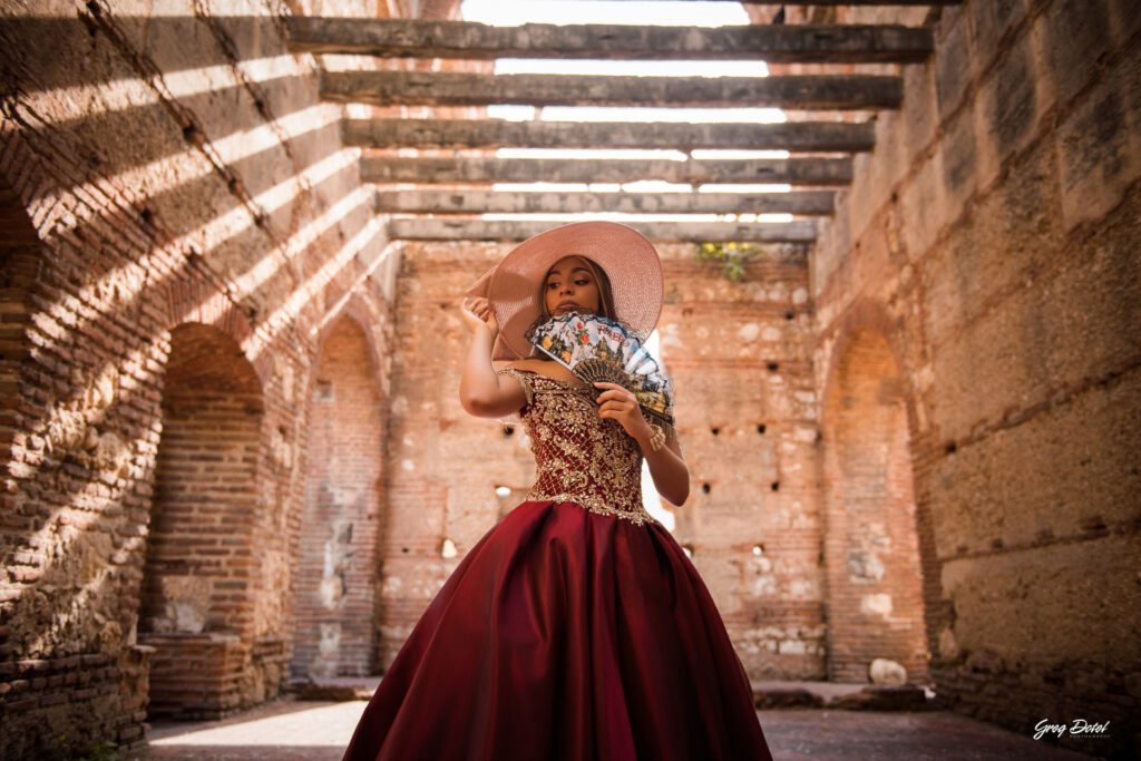 Quinceañera en las Ruinas del Hospital San Nicolas de Bari en la Zona Colonial de Santo Domingo, República Dominicana en su sesión de fotos profesional con elegante vestido rojo de 15 años